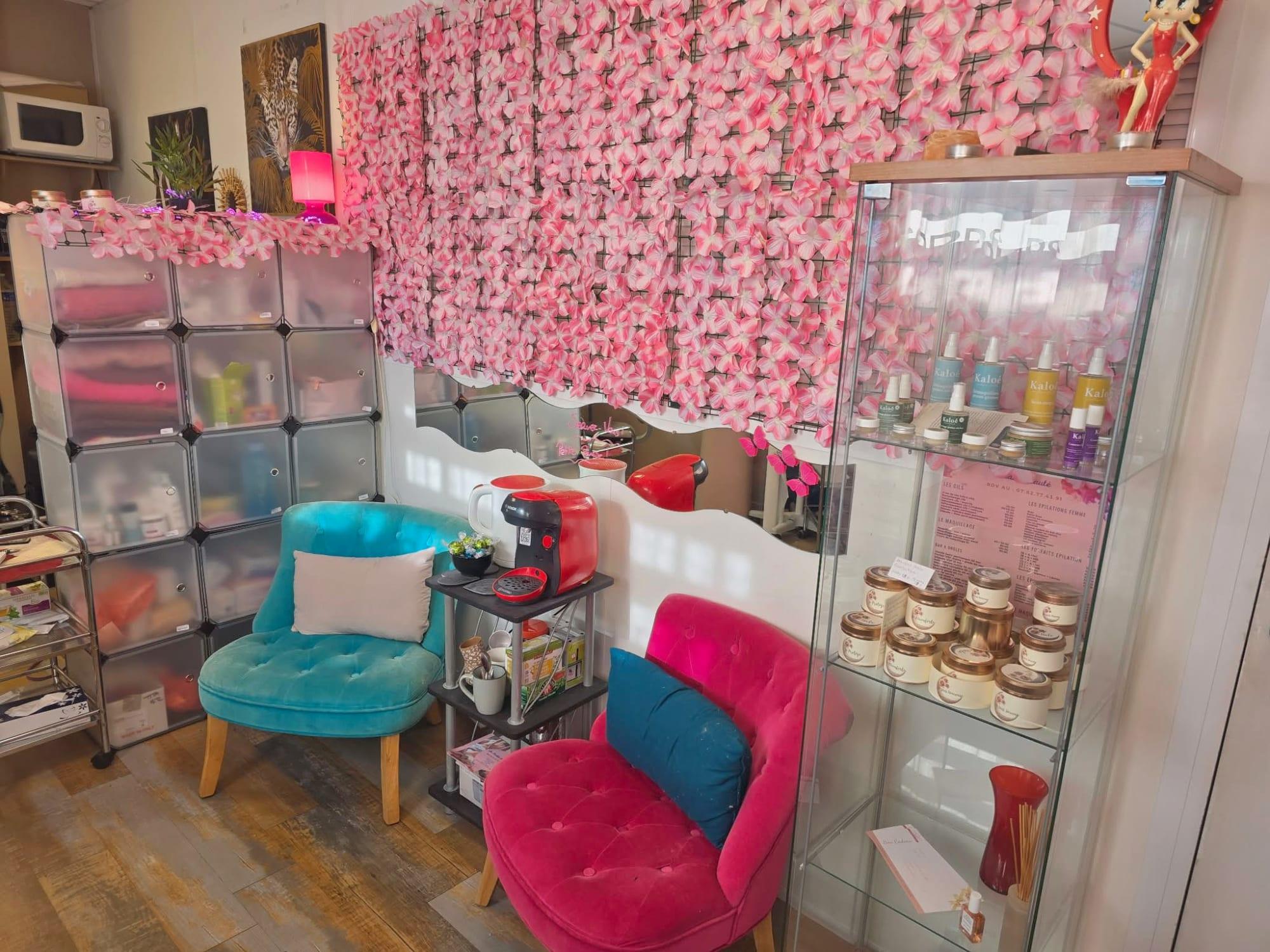 Le mur de fleurs roses et l'espace d'attente de l'institut Au Studio Beauté à Jacou